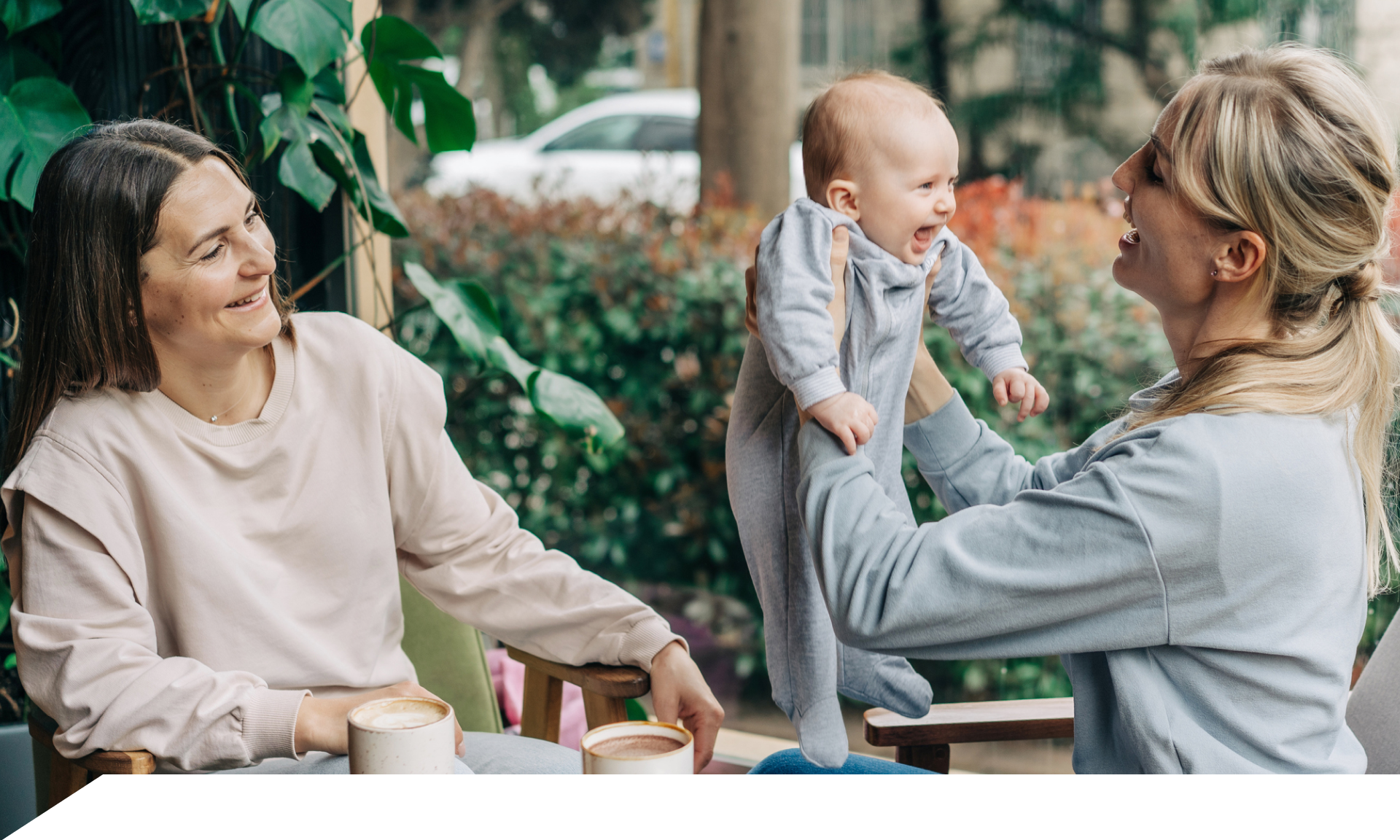 Two women sitting outside, one holding a baby