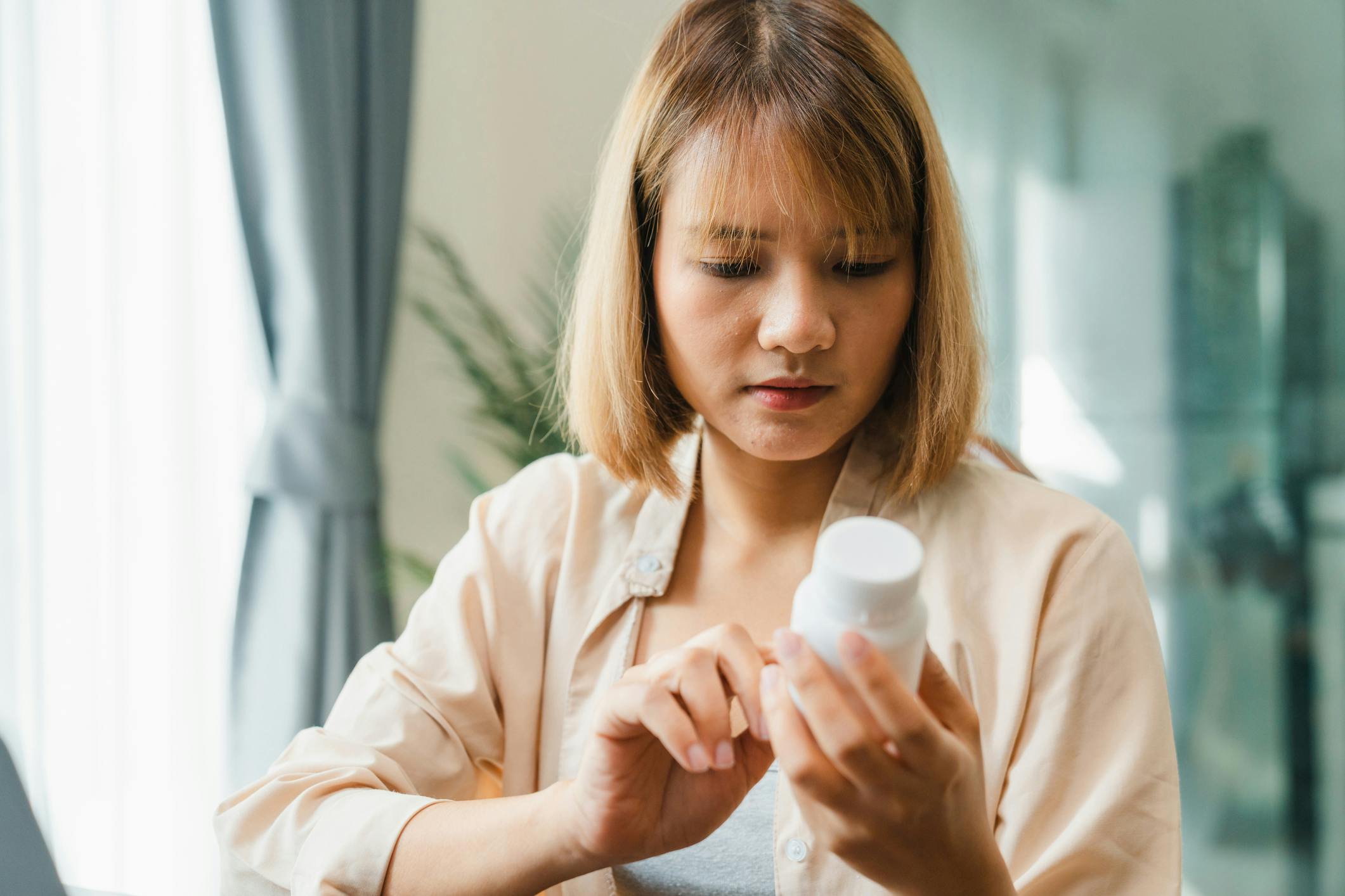 A woman holding a supplement bottle reading the label 