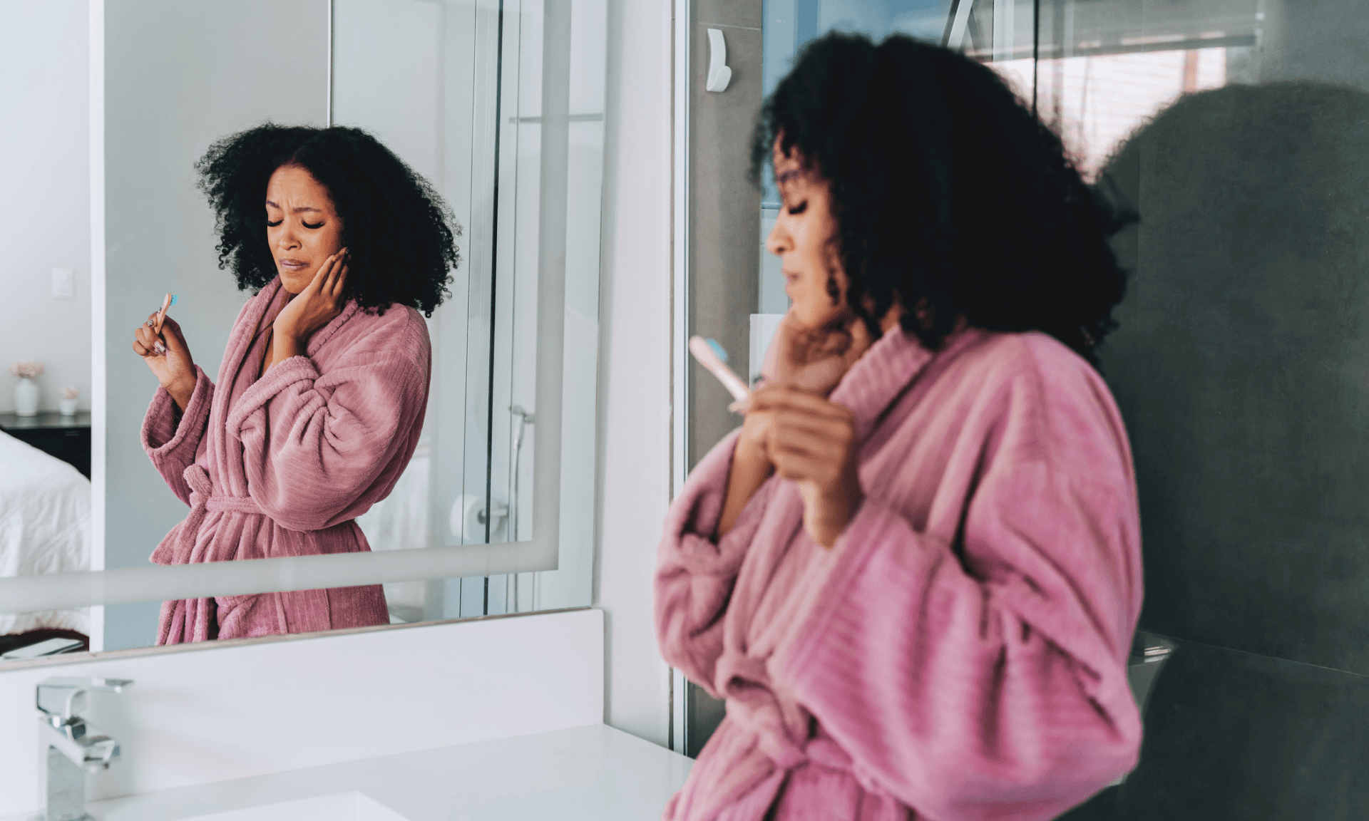 A woman standing in the bathroom with one hand on her jaw