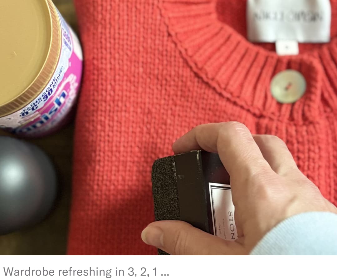 Hand using a sweater stone to remove piling from red sweater.