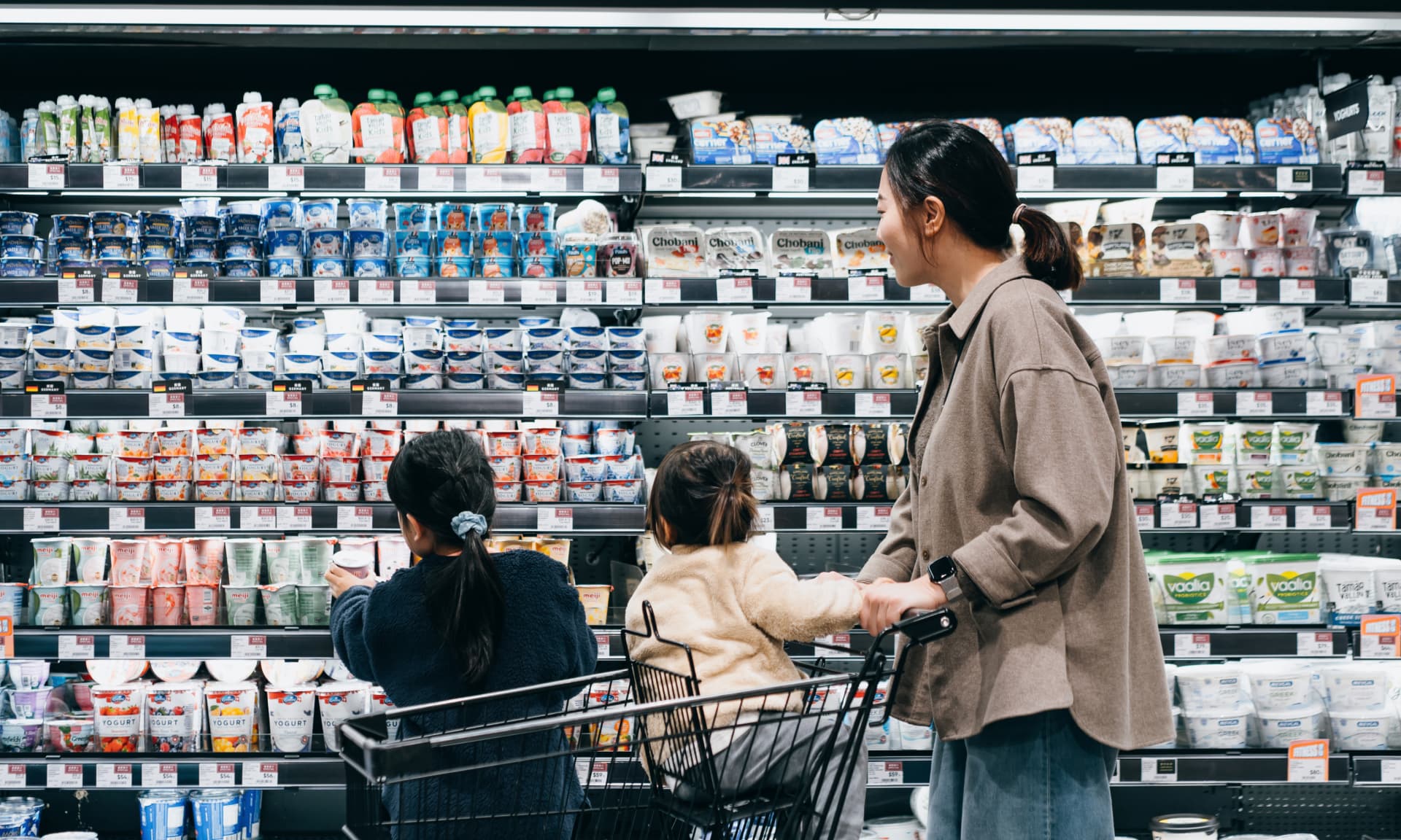 Woman with kids in cart at the grocery store dairy aisle